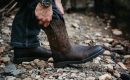 man putting on pair of Ariat boots